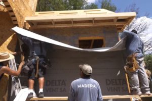 construction workers applying the DELTA®-VENT SA house wrap over the window opening
